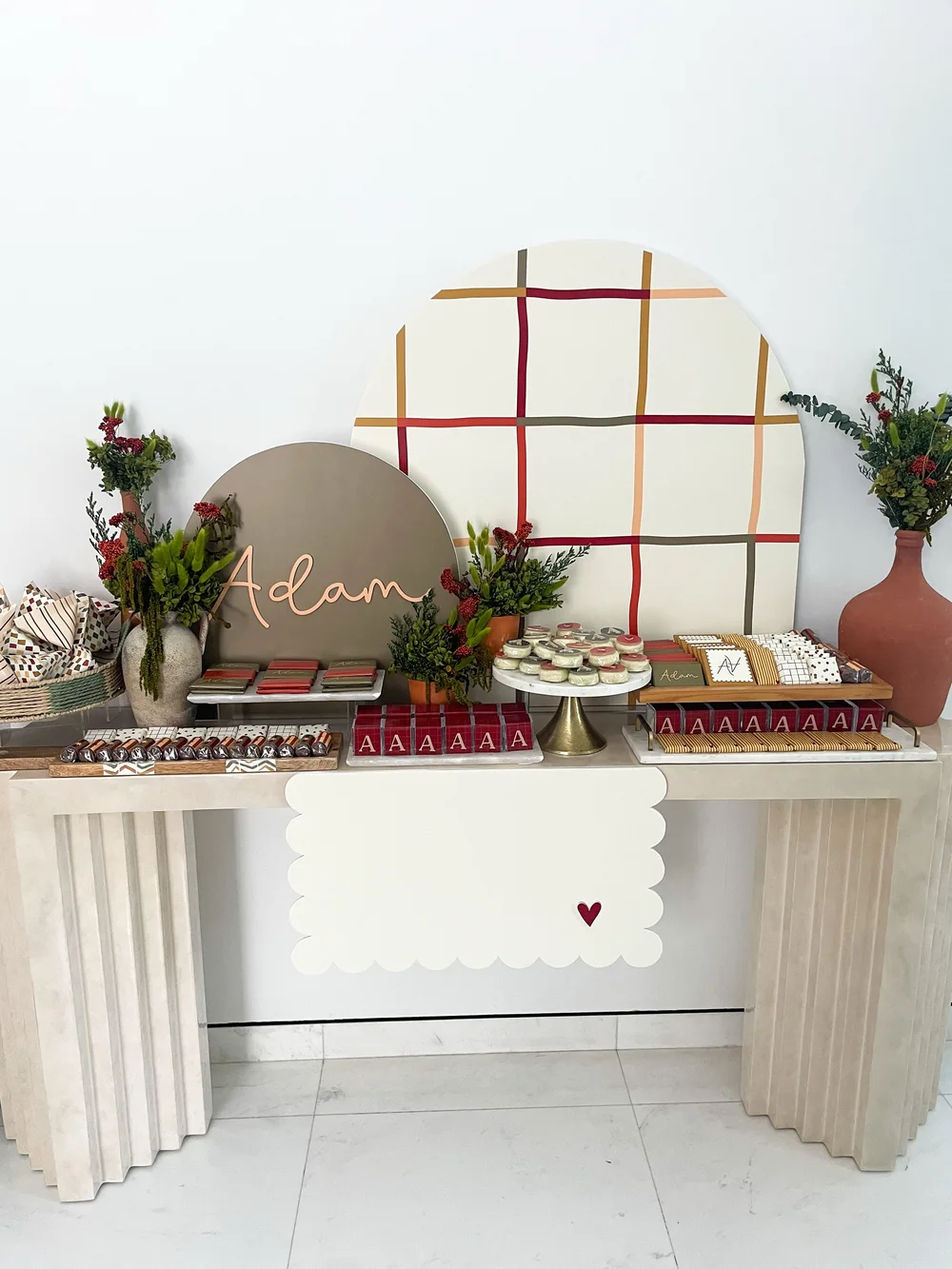 A newborn welcoming console with a name arch, grid backdrop and dessert trays