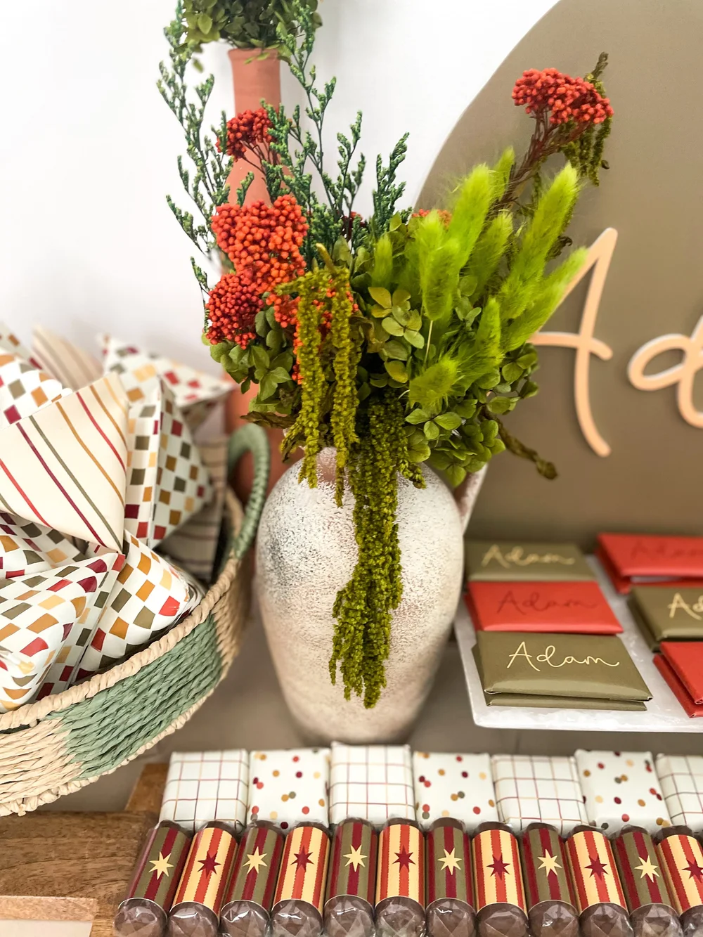 Favour boxes, patterned chocolates and a full floral arrangement on a styled console