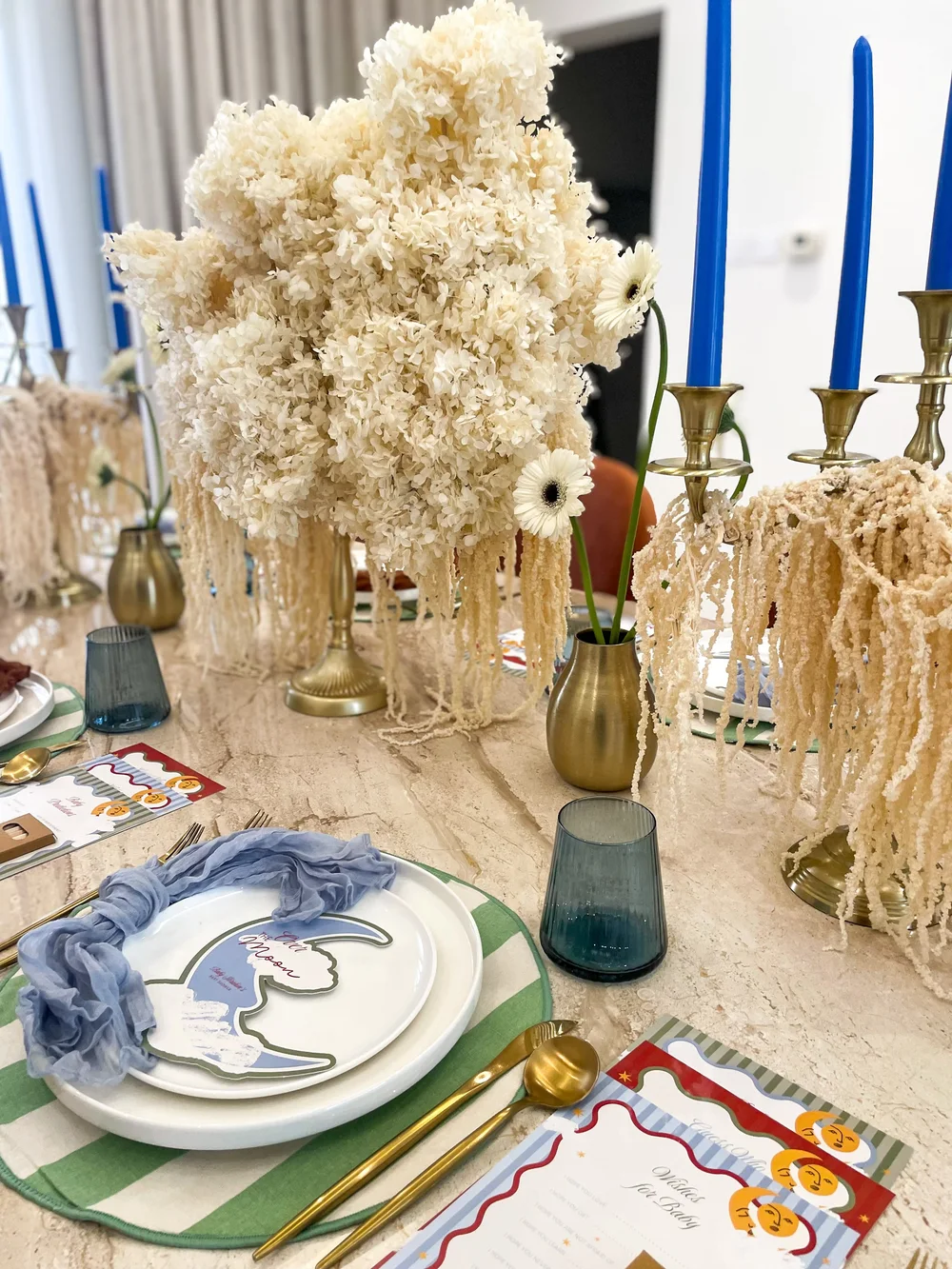 Dried florals, blue taper candles and brass holders on a baby shower table