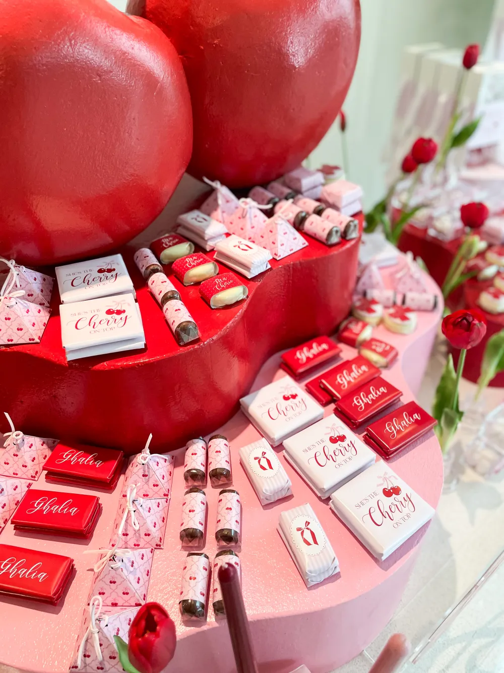 A cherry themed chocolate and dessert display in red and pink