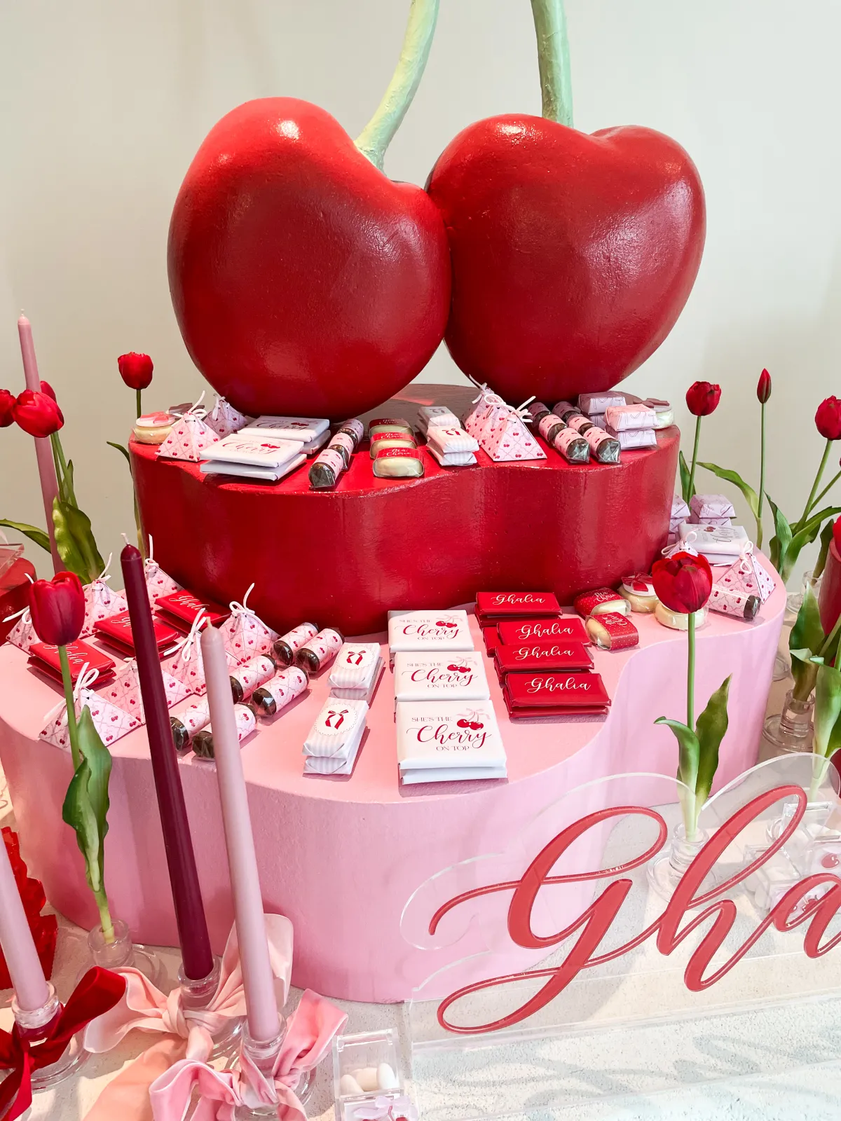 A pink and red cherry newborn welcoming centrepiece on a plinth