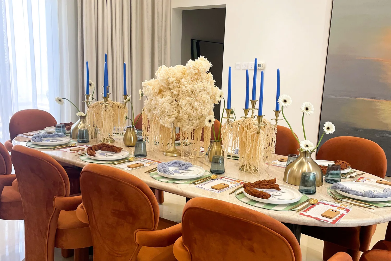 A baby shower table styled with terracotta chairs, blue taper candles and dried florals