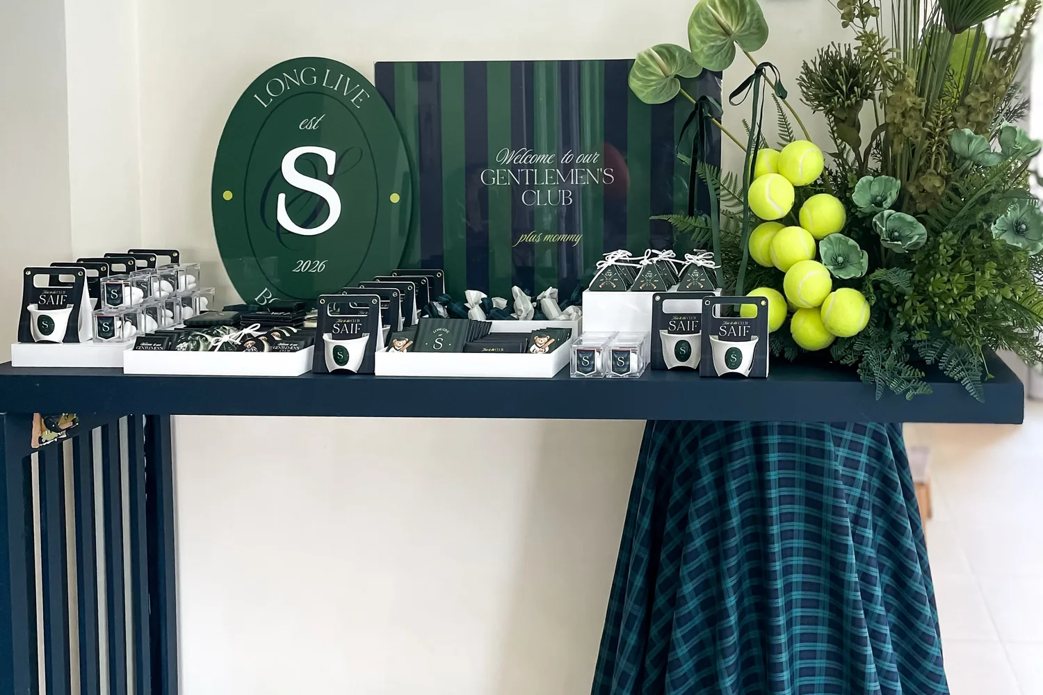 A gentlemen's club themed newborn welcoming seen wide, with a monogram sign and a draped console