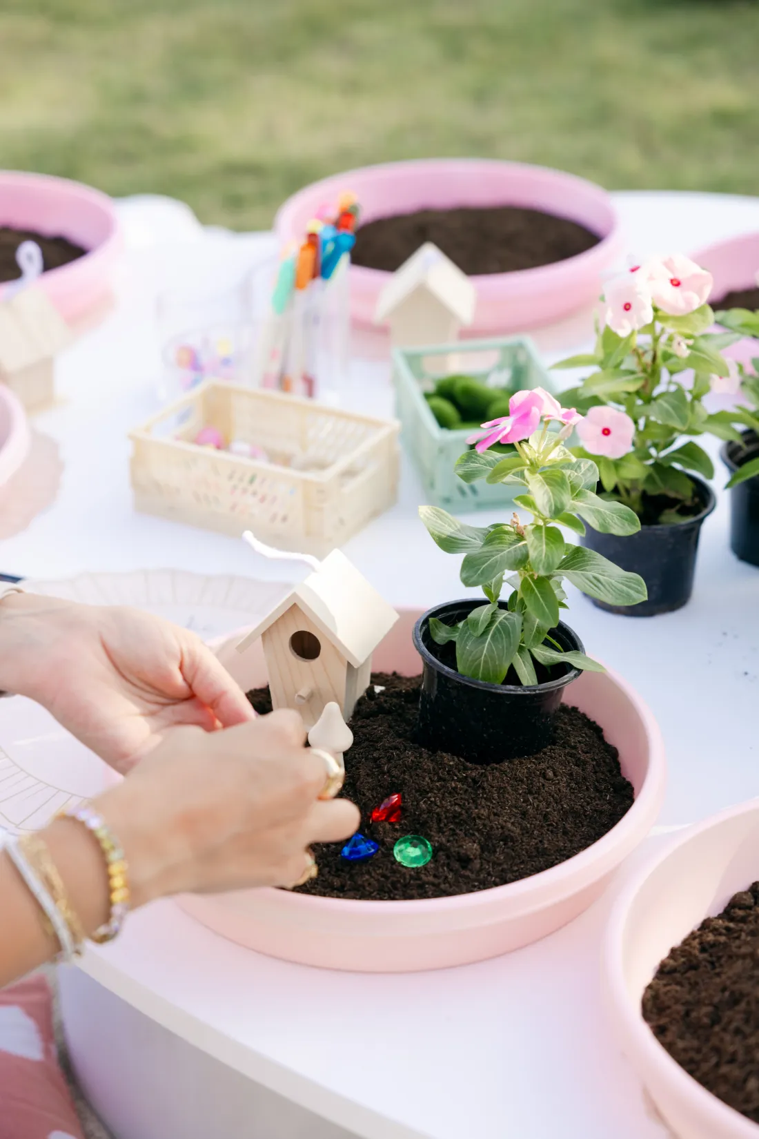 Hands placing the small details of a hand-made fairy garden setup